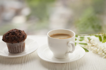 Top view on cup of coffee and chocolate cupcakes on white background. Cup of black coffee with chocolate muffins.