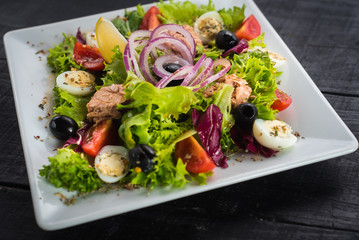 Salad with pieces of meat and vegetables on wooden background