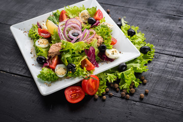 Salad with pieces of meat and vegetables on wooden background