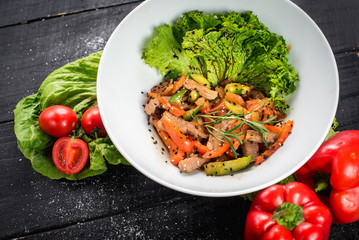 Salad from meat with red pepper and soy sauce on wooden background