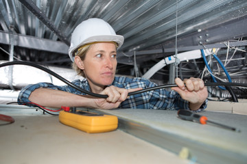 female electrician wiring inside ceiling