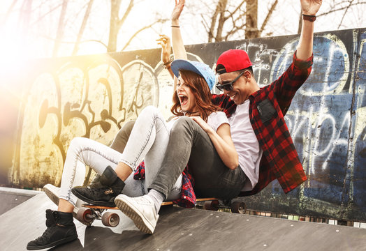 Young teen couple sitting on ramp and hangout at the skate park .Laughing and fun.