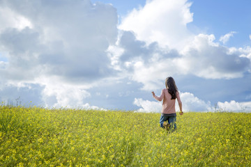 Fototapeta premium happy girl in a yellow flower field with a dandelion in her hand