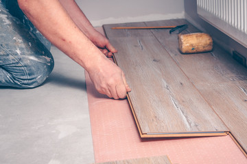 Fototapeta na wymiar Working with hands installs a laminate board, professional flooring installation