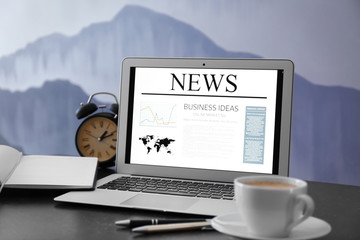 Workplace with laptop and news on screen