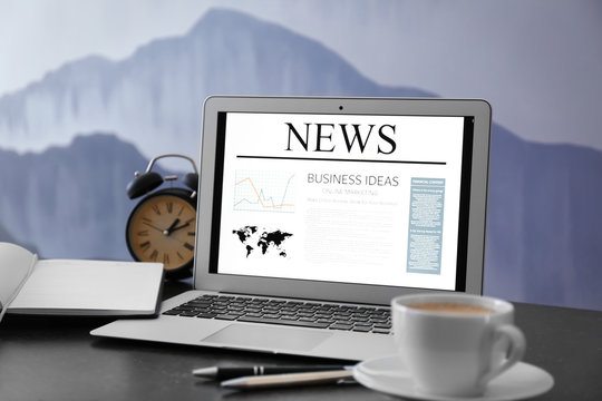 Workplace with laptop and news on screen