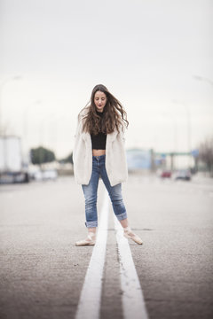woman dancer with ballet tips, jeans and white coat on the street and look down vertical format