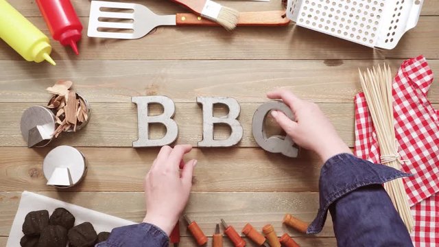 Metal BBQ sign with grilling tools on wood background