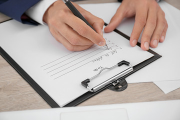 Man making to-do list while sitting at table, closeup