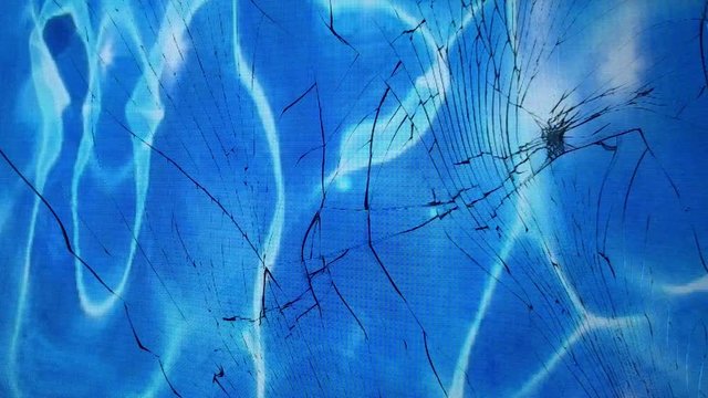 view of the blue water in the pool through broken glass