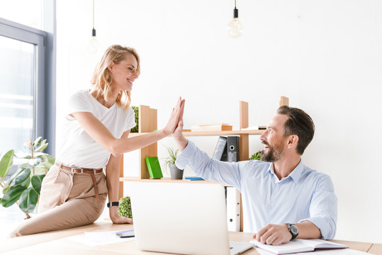 Couple of excited colleagues giving high five