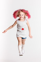 Colored wavy hairs. Little modern hipster girl in fashion clothes, jumping in studio