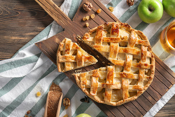 Wooden board with tasty apple pie on table