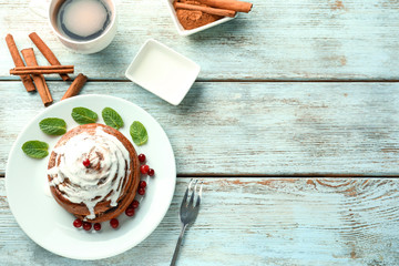 Plate with glazed cinnamon bun and cranberries on table