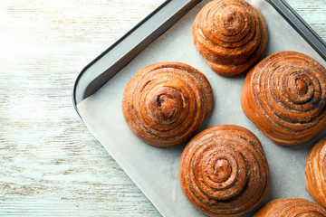 Baking tray with sweet cinnamon buns on table