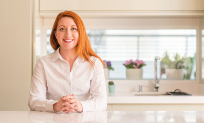 Redhead woman at kitchen with a happy and cool smile on face. Lucky person.