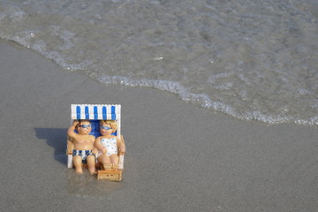 Happy couple makes beach holiday. 
Ein Urlauberpaar sitzt glücklich lächelnd im Strandkorb.
