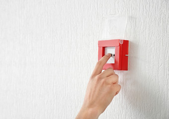 Young man using fire alarm system indoors