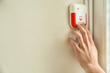 Young woman using fire alarm system indoors