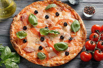 Tasty pizza and ingredients on wooden table
