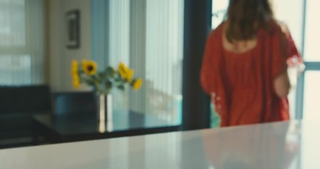 Young woman taking watermelon from the kitchen to balcony