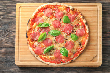 Wooden board with tasty pizza on table