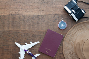 Creative flat lay travel concept, passport book, compass and binoculars on wooden background with copy space