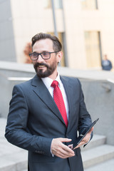 Close-up of businessman using a digital tablet at work. Portrait of handsome bearded businessman outdoor.