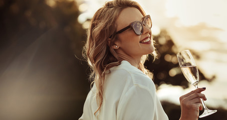Smiling woman in sunglasses drinking wine - Powered by Adobe