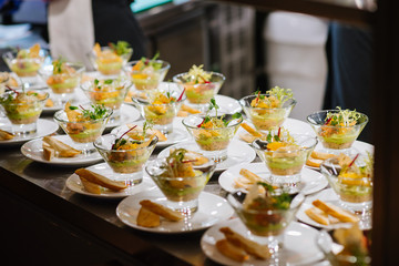 Tasty little snacks with meat and vegetables on served table at the restaurant
