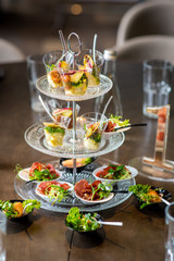 Tasty little snacks with meat and vegetables on served table at the restaurant