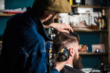 Hipster bearded client getting hairstyle. Barber with hairdryer drying and styling hair of client....