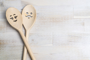 Wooden spoon with funny faces, woman and man, on wooden background