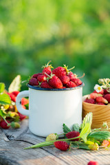 Wild strawberry in a mug on a old table. Summer food.
