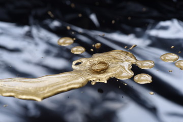 Drops of golden paint, polish, lacquer on glossy black background.