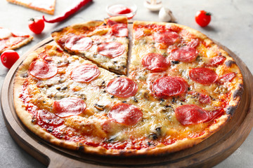 Wooden board with tasty pepperoni pizza on table