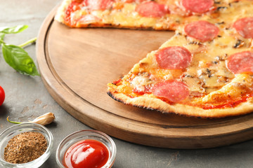 Wooden board with tasty pepperoni pizza on table