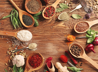 Composition with different spices in spoons on wooden background