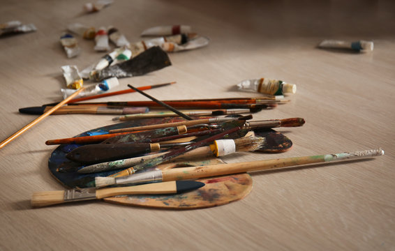 Palette with tools and paints on floor in workshop