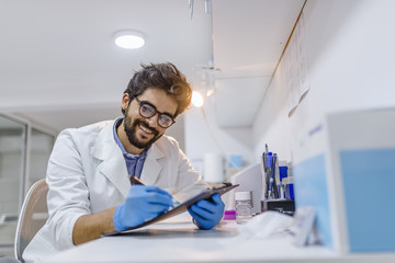 Male doctor consults with his patient and writes notes on the clipboard