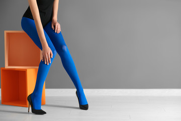 Legs of beautiful young woman in tights against color wall