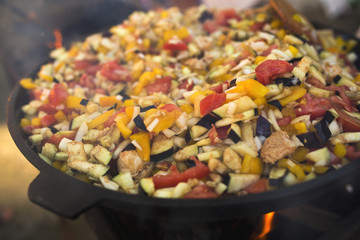 Vegetables with meat in a cauldron on a fire
