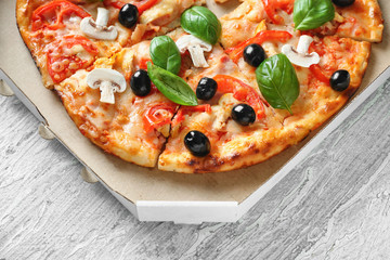 Box with tasty Italian pizza on table
