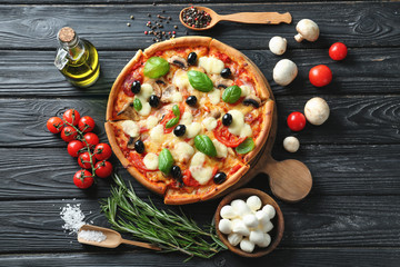 Tasty Italian pizza and ingredients on wooden background