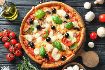 Tasty Italian pizza and ingredients on wooden background