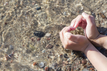heart of the hands on the background of the sea shore.
