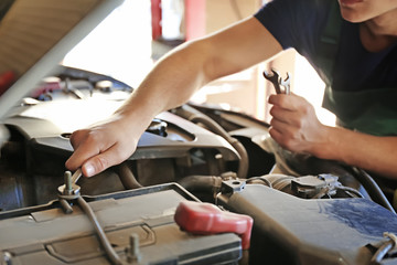 Auto mechanic repairing car in service center, closeup