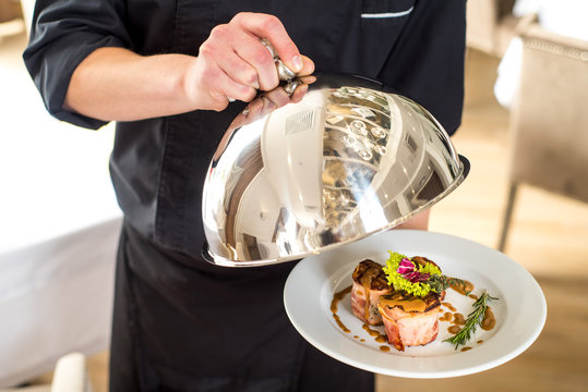 A chef or vaiter holding and shows a dish