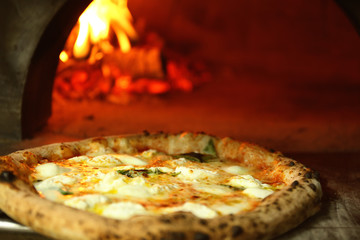 Tasty pizza near firewood oven in kitchen