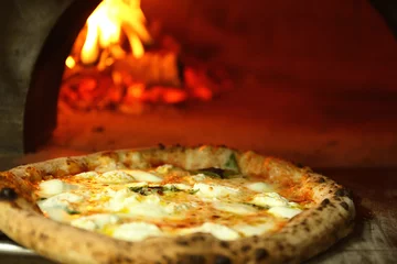 Selbstklebende Fototapeten Tasty pizza near firewood oven in kitchen © Pixel-Shot